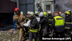 Bomberos trasladan un cuerpo que sacaron que entre los escombros de un edificio residencial alcanzado por un ataque ruso, en Uman, en el centro de Ucrania, el 28 de abril de 2023. (AP Foto/Bernat Armangué)