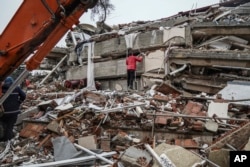 Un hombre busca sobrevivientes entre los escombros de un edificio, en Gaziantep, Turquía. (AP Foto/Mustafa Karali)